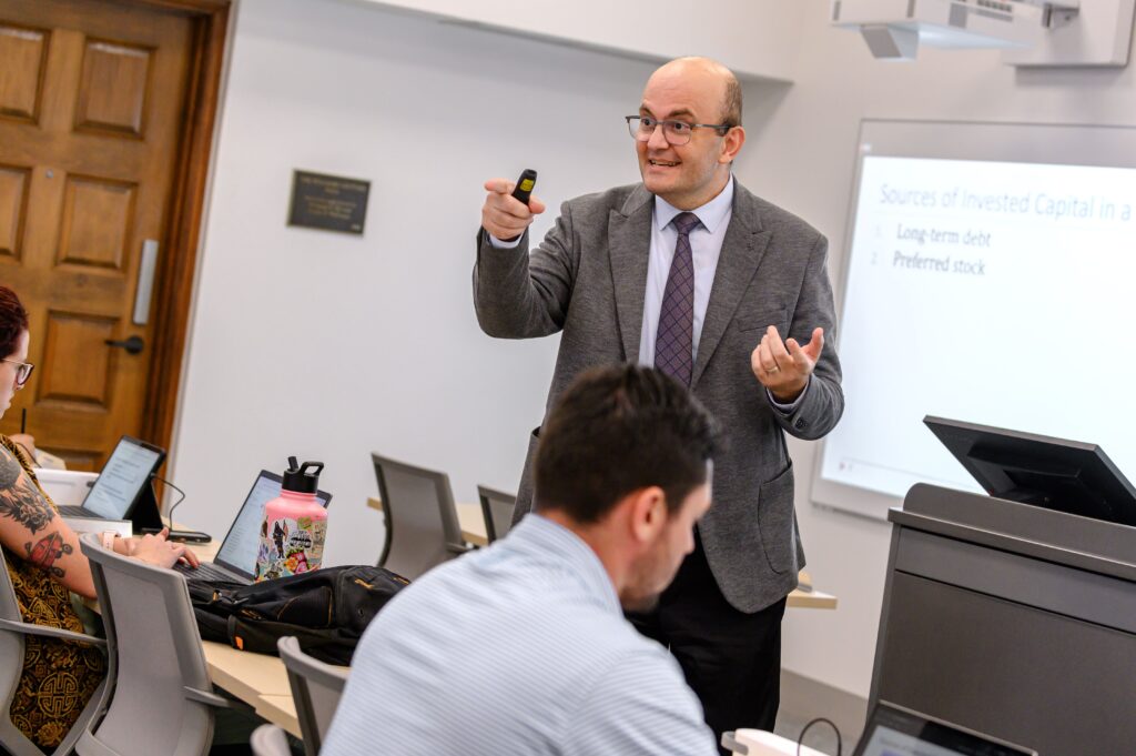 professor koray simsek stands in front of a class gesturing with his hands