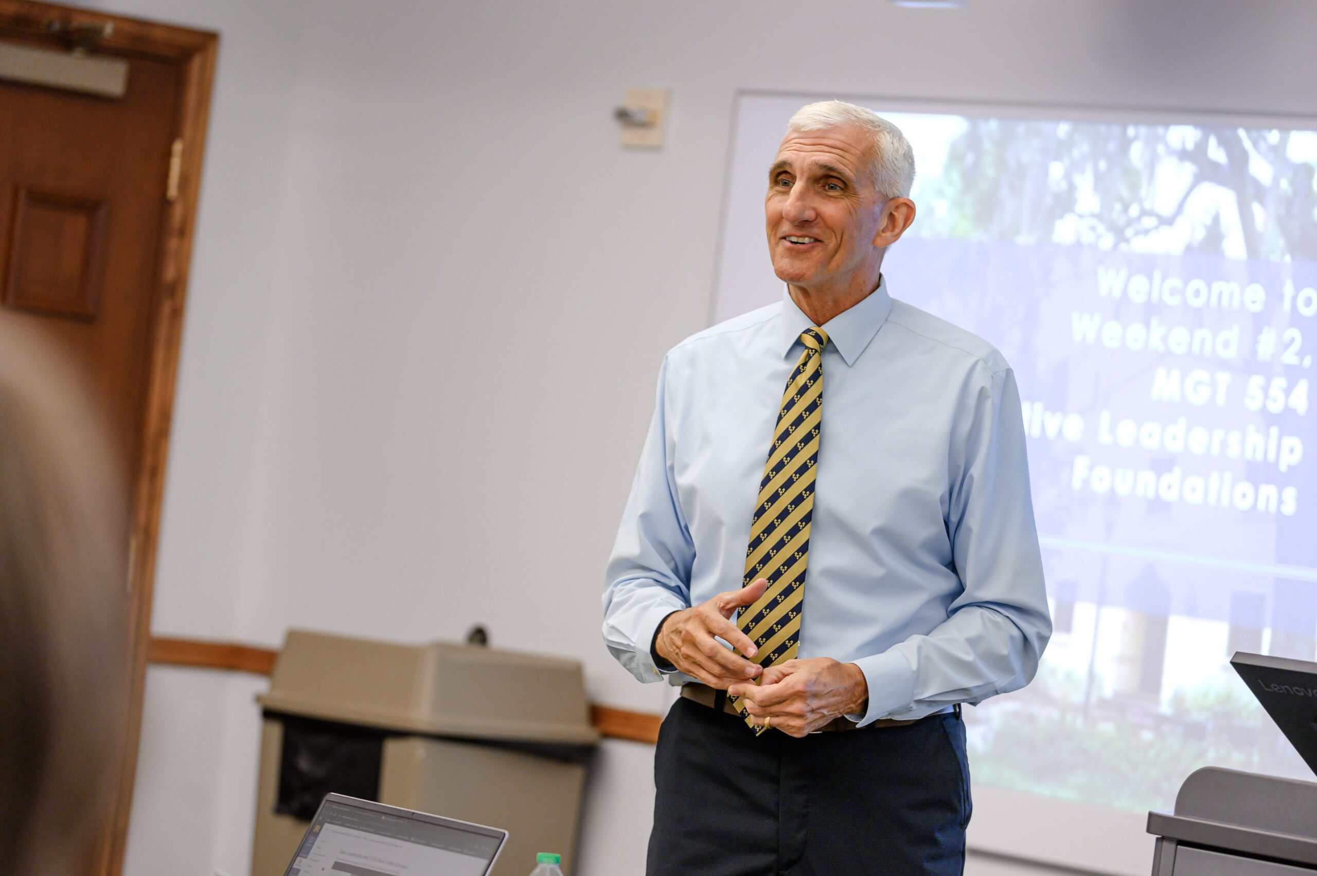 mark hertling stand in the front of a crummer classroom smiling and teaching