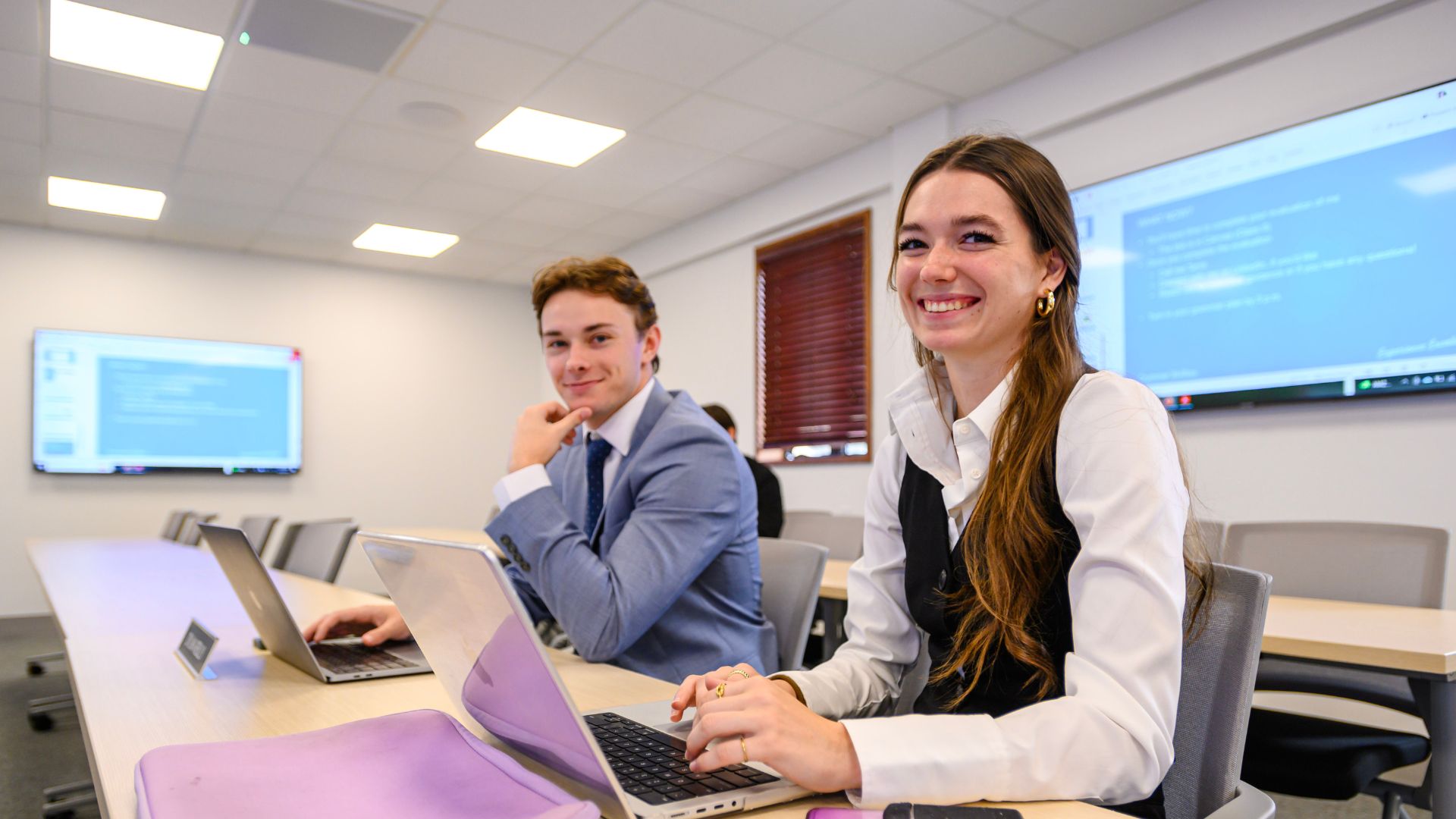 a female student smiles while working on purple laptop