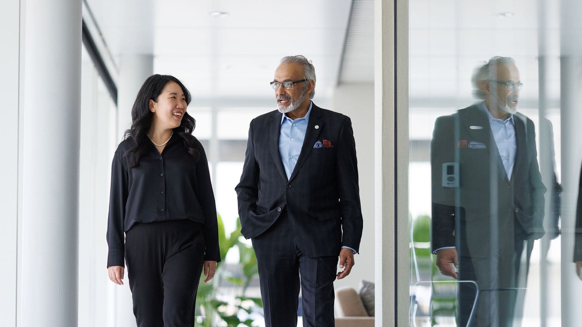 dean anil menon walks with EBI director min sun kim in a brightly lit hallway