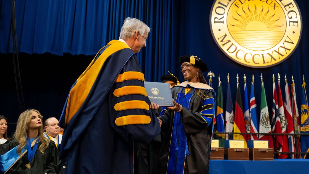 MBA graduate accepting a diploma from Rollins College president Cornwell at a commencement ceremony.