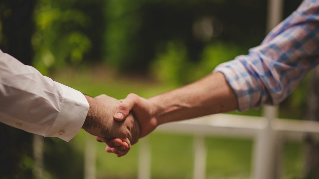 Close-up of two people shaking hands on an agreement outdoors.