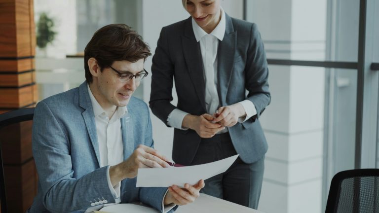 Two business professionals reviewing a document together in an office.